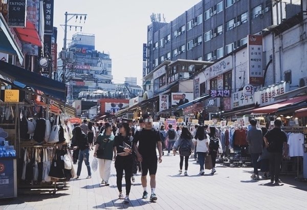 Hongdae street in Seoul with tourists walking through a lively shopping and street market area near Hongik University