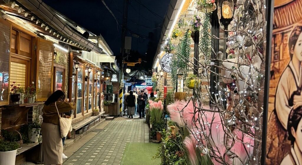 Night view of Ikseon-dong Hanok Street in Seoul with traditional shopfronts, warm lights, and narrow alley atmosphere