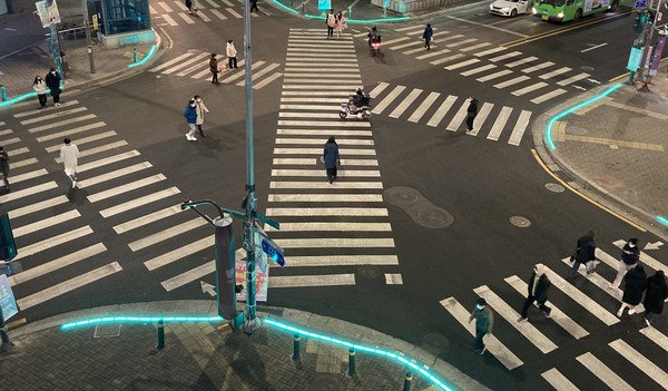 Seoul crosswalk with floor-level traffic lights embedded along the curb to help pedestrians notice traffic signals more easily at night.