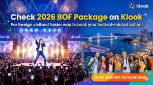A promotional banner for the 2026 Busan One Asia Festival (BOF) on Klook. The image features a K-pop concert stage with a performer and cheering fans, alongside a group of diverse foreign tourists at Busan's Haeundae beach with Gwangandaegyo Bridge in the background. Text reads 'Check 2026 BOF Package on Klook' with a 'Book Now' button.